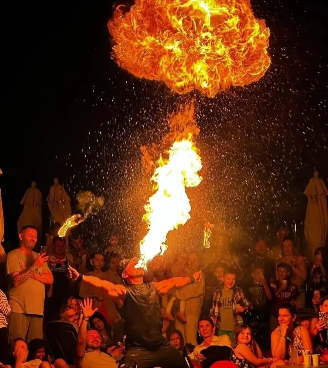 Fire breather performing for a crowd at night