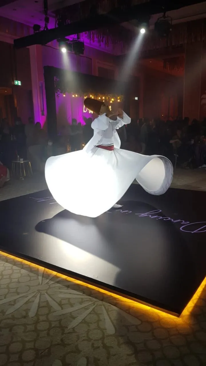 Sufi whirling dancer in a white robe on a lit stage